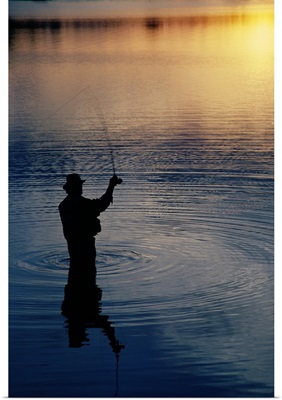 Rear view of fly-fisherman silhouetted by sunrise, Mauthe Lake, Kettle Moraine State Forest, Wisconsin