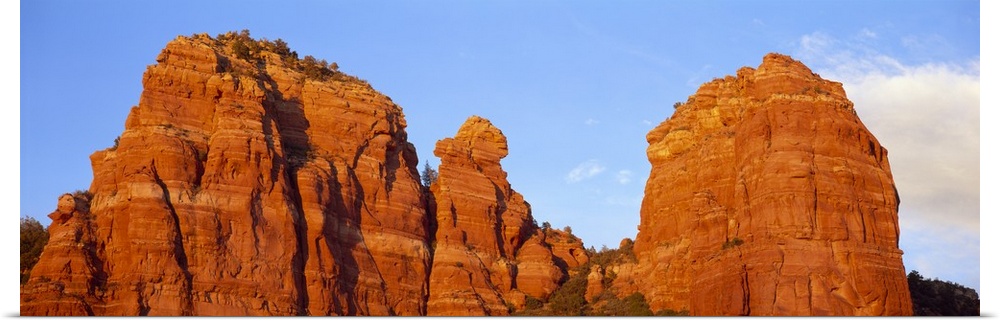Panoramic photograph of giant rock formations beneath an almost clear blue sky, in Sedona, Arizona.