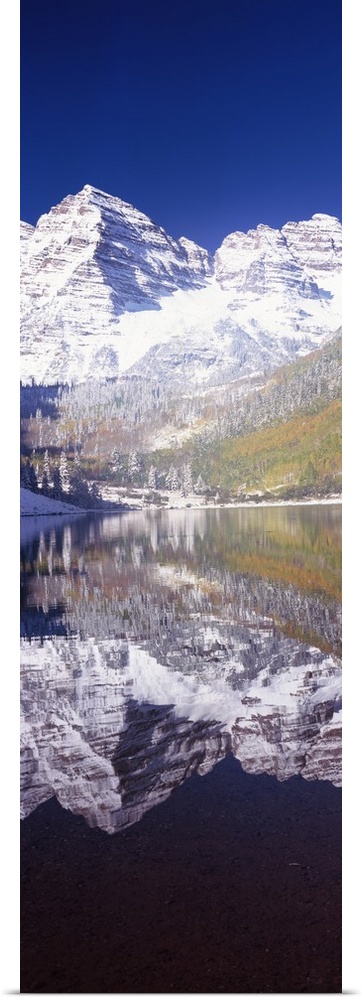 Vertical panoramic photograph of snow covered mountain that is reflected in the water below.