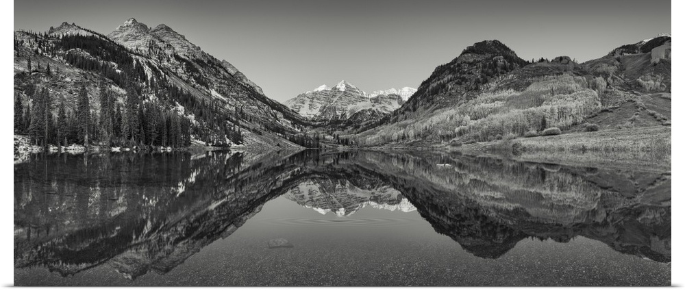 Black and white photograph taken of large mountains and terrain that reflect perfectly in the still water below.