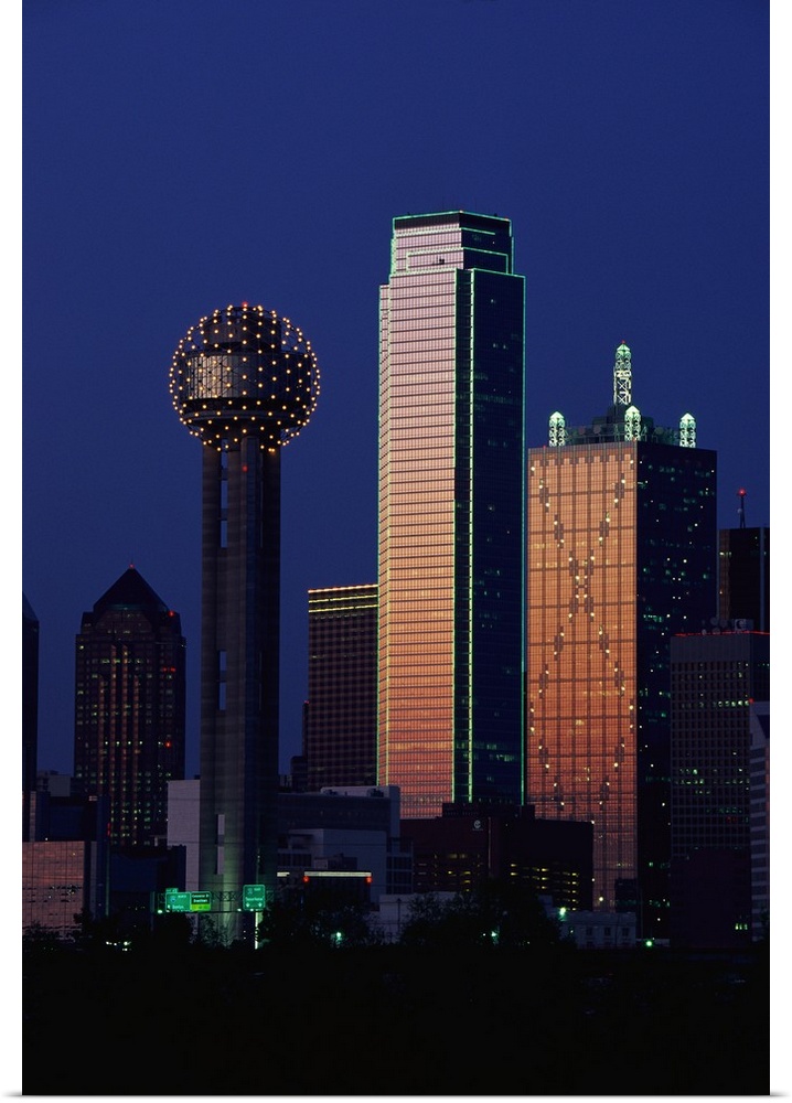 This large vertical piece is a photograph that has been taken of the Dallas skyline with the buildings illuminated under a...