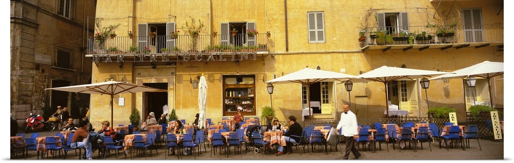 Panoramic photo on canvas of people dining in an outside cafo area in Italy with old buildings in the background.