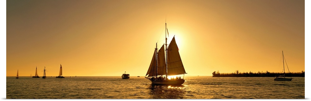 A sail boat with multiple masts photographed at sunset it in the Florida Keys on panoramic wall art.