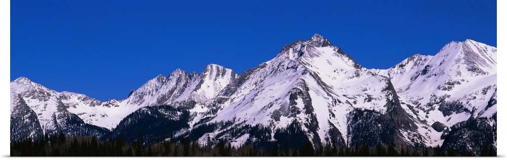 Snow capped Mountain range protrudes in to the brilliant blue sky in Colorado.