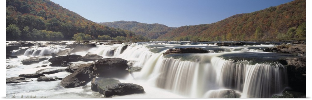 Panoramic image on canvas of long waterfalls with rolling mountains of fall foliage in the background.