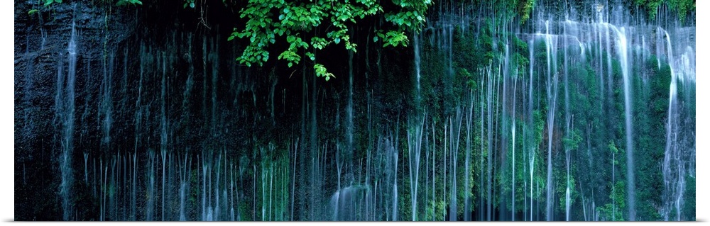 Panoramic photo of little waterfalls trickling down a cliff in Japan.