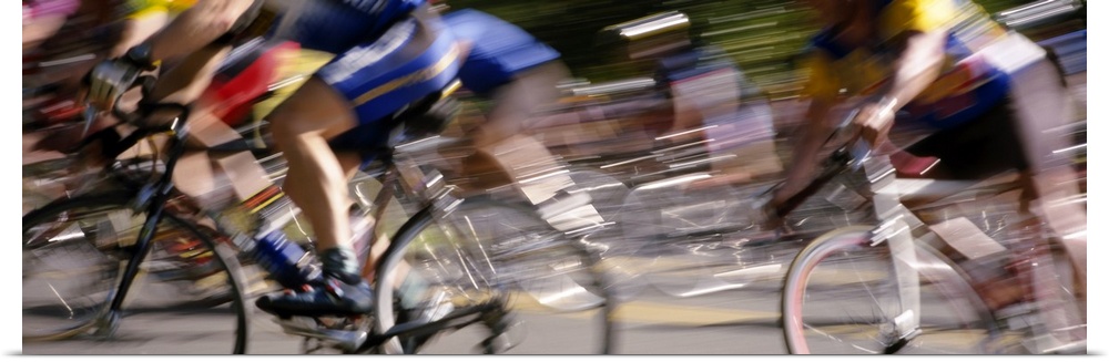 A panoramic photograph of racers on bicycles moving through the frame, blurred with motion.