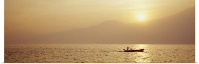 Silhouette of a fishing boat in a lake at sunrise, Lake Garda, Italy