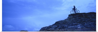 Silhouette of a mountain biker standing on a cliff, Kansas