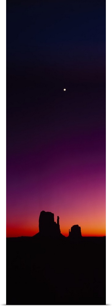 Vertical panorama of a crescent moon hanging in the sky high above the rock formation, The Mittens, as the last glow of su...