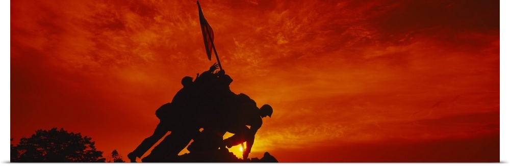 Big, panoramic photograph of the silhouette of the Iwo Jima Memorial, against a fiery sunset in  Arlington National Cemete...
