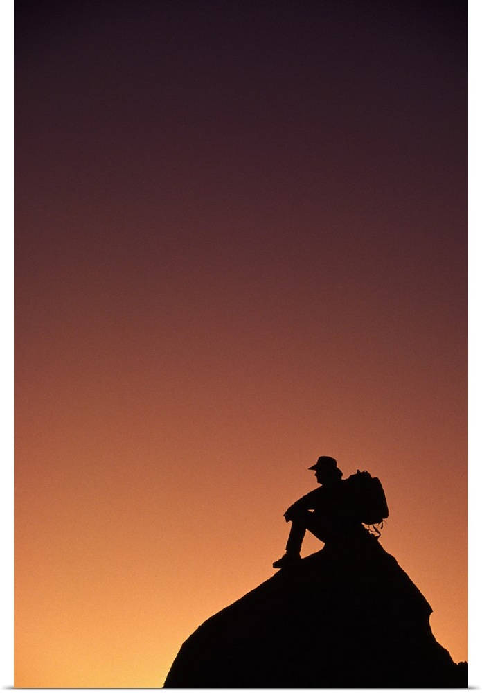 Silhouetted backpacker on rock, sunset light, Utah