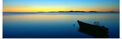 Silhouetted boat moored in Chukchi Sea at sunset, distant Mulgrave Hills, Alaska