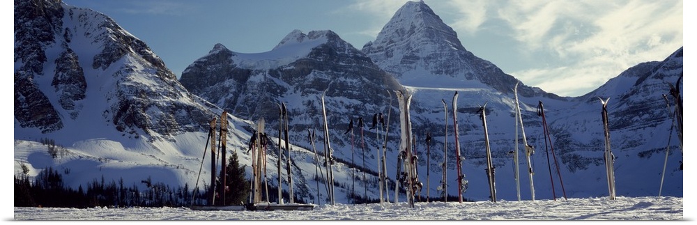 Panoramic photo canvas of snowy mountains in the distance and ski equipment sticking out of the snow in the foreground.