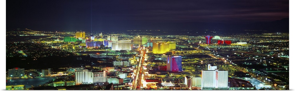 Giant horizontal panoramic photograph of the Las Vegas, Nevada (NV) skyline and surrounding areas all lit up at night.