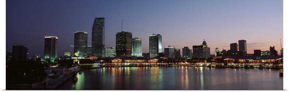 Long print of a cityscape along the water in Florida lit up at dusk.