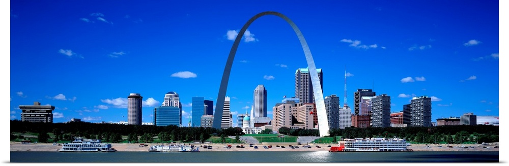 Panoramic photograph of downtown district skyline and iconic arch on a sunny day with waterfront.