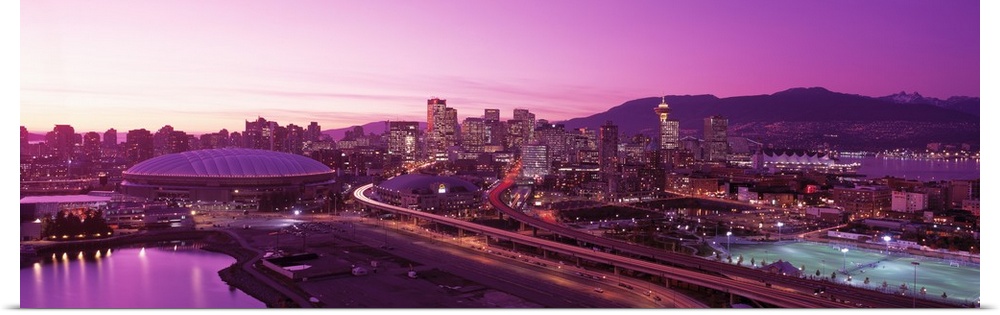 An aerial panoramic photograph taken of the skyline in Vancouver that has a purple hue from the sunset.