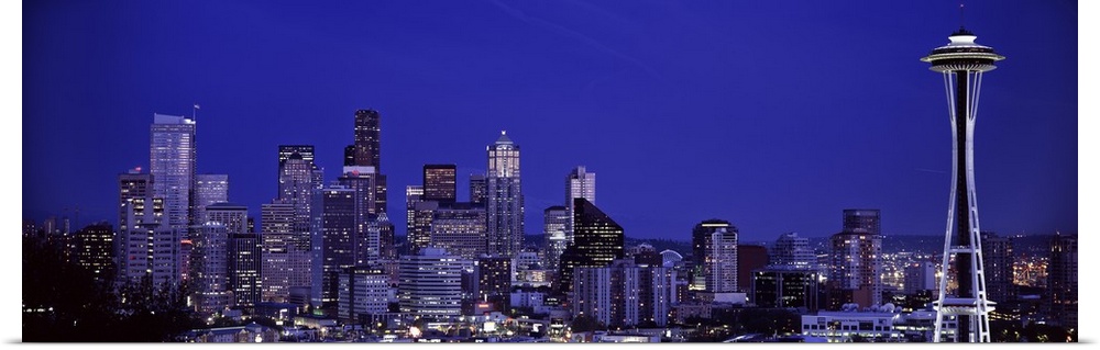 Panoramic photograph of skyline at night with buildings lit up.  Iconic buildings such as the Space Needle and others glow...