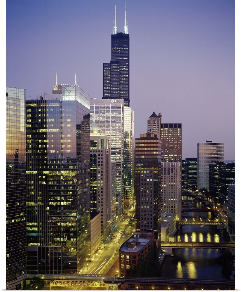 Vertical photograph of several towering buildings in the urban city of Chicago at twilight.