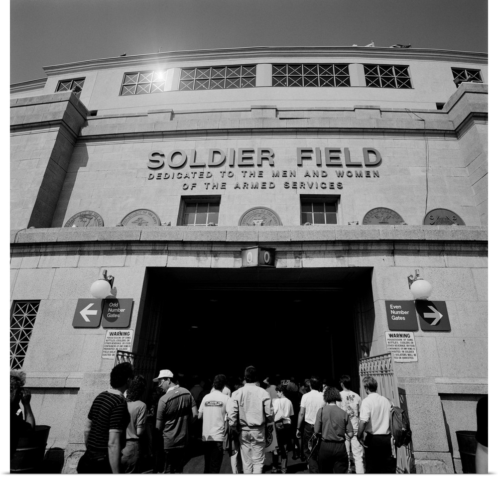 A black and white photograph of fans entering the Chicago Bears stadium with the fields name displayed just above them.