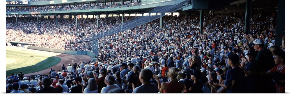 Panoramic, big photograph of packed stands of fans watching a baseball game at Fenway Park, in Boston, Massachusetts.