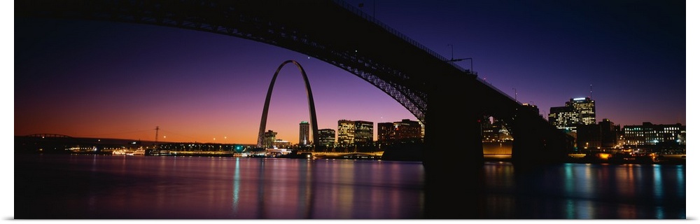 A dramatic panorama of downtown St. Louis including bridges, the arch and sunset.