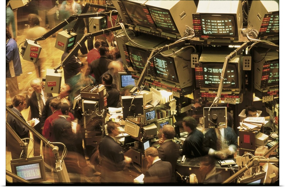 This is a retro photograph of the trading floor in New York from the 1980s where brokers are working in cluttered workspac...