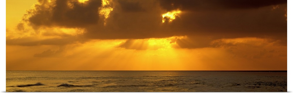 Sunbeams radiating through clouds over the ocean