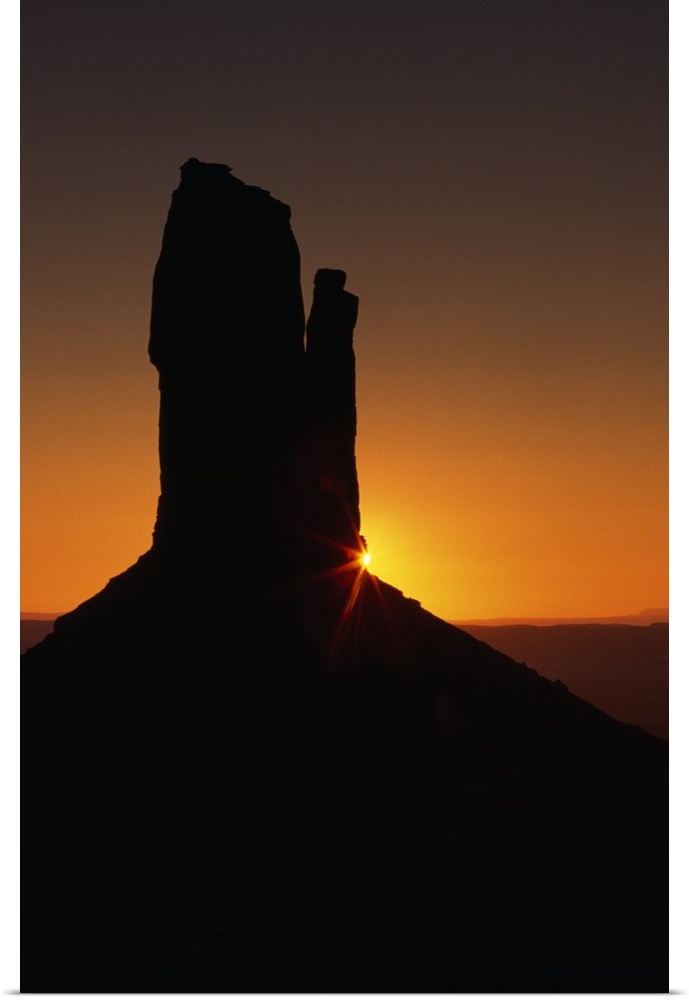 Sunrise behind silhouetted sandstone formation, Monument Valley, Utah
