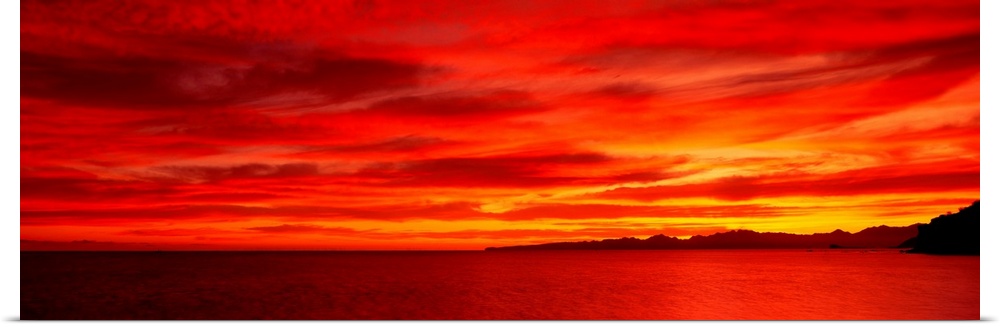 Large wall image of a deep warm sunset over the ocean with a little strip of land on the right side jetting out.