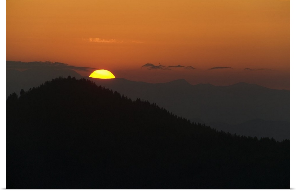 This landscape photograph captures the sun rising above the silhouettes of Appalachian mountains.