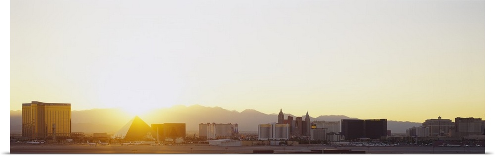 Panoramic picture taken of the strip in Las Vegas with a bright sun setting behind the mountains in the distance.