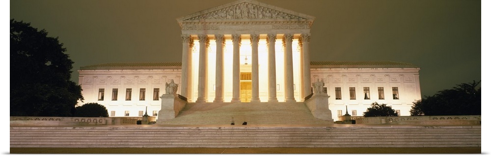 Large, panoramic, low angle photograph of the Supreme Court Building in Washington DC, brightly lit at night.