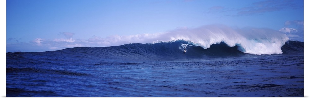 Panoramic image of a surfer riding a large breaking wave.