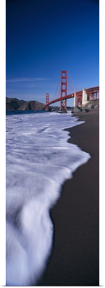 Large, vertical photograph looking down the shoreline of the San Francisco Bay, the Golden Gate Bridge in the background b...