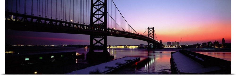 Long horizontal photo print of a big bridge in Philadelphia reaching across a river at sunset.