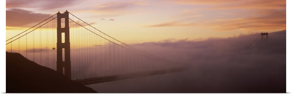 Panoramic photo on canvas of the silhouette of the Golden Gate Bridge coming out of the fog at sunset.