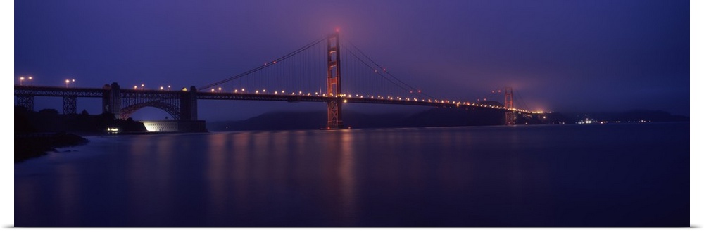Suspension bridge lit up at dawn viewed from fishing pier Golden Gate Bridge San Francisco Bay San Francisco California