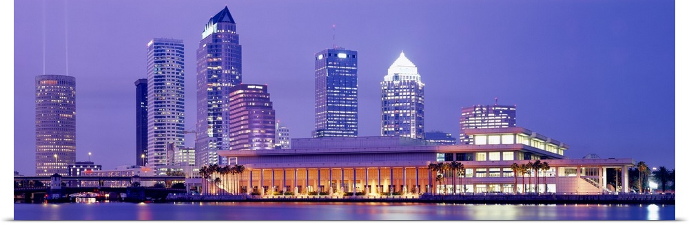 The Tampa skyline is photographed in panoramic view during the night with the buildings all illuminated.
