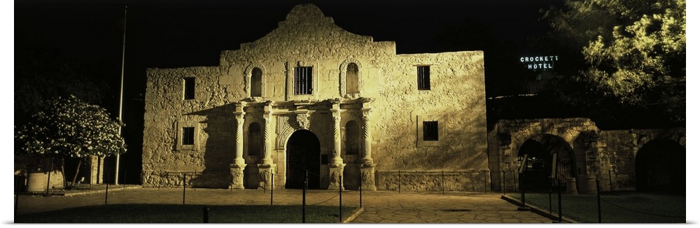 Large, panoramic photograph of New Mexico's famous Alamo, shone in the light as it is surrounded by the blackness of night...