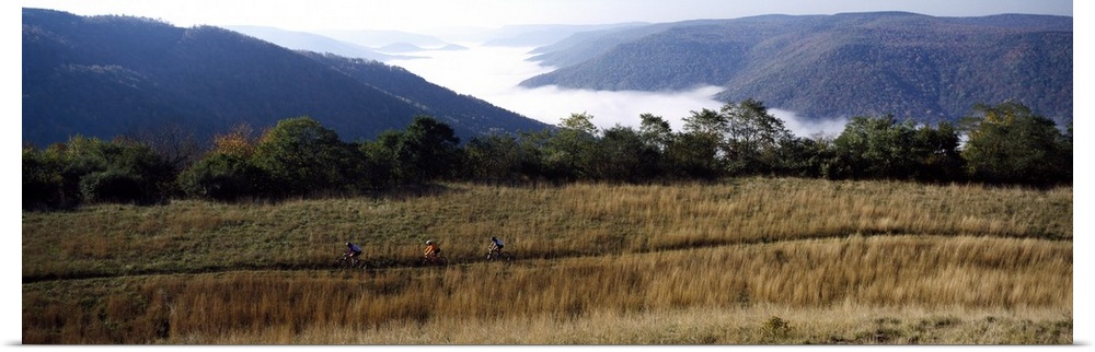 Three people cycling with mountains in the background, West Virginia
