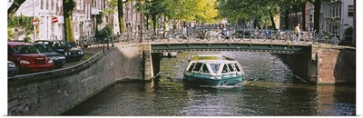 Tourboat under a bridge in a channel, Amsterdam, Netherlands