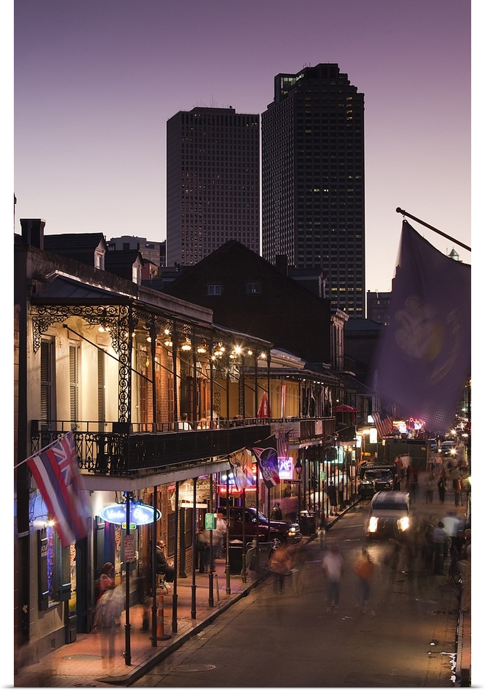 People stroll down Bourbon Street in the French Quarter in New Orleans, Louisianna (LA) at dusk with skyscrapers looming i...