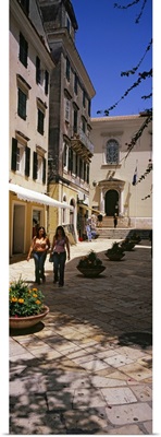 Two women walking in front of a courtyard in Corfu Old Town, Corfu, Greece