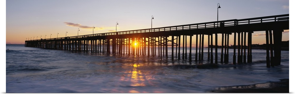 Panoramic photo on canvas of the silhouette of a pier going out into the ocean against a sunset.