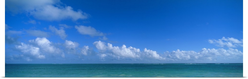 Panoramic photograph of ocean under a cloudy sky.