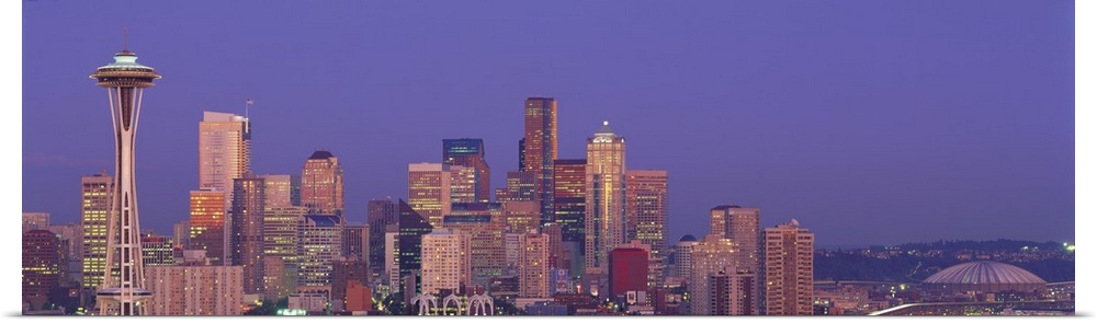 Panoramic photograph of lit up skyline at dusk with iconic buildings such as the Space Needle, Columbia Center, Smith Towe...