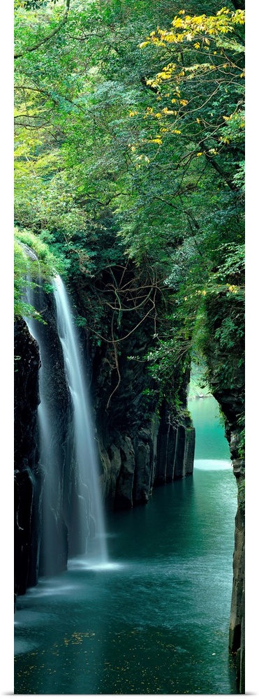 Vertical outdoor shot of a forest, river, and waterfall taken with time-lapsed photography.