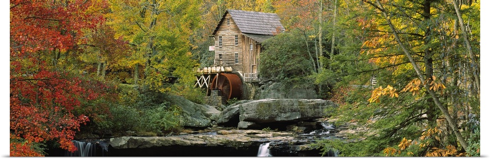 Panoramic photograph of mill in forest surrounded by fall foliage.